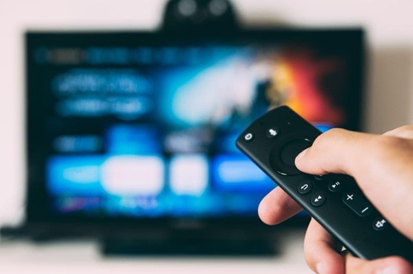 Cliente usando el control remoto frente al televisor
